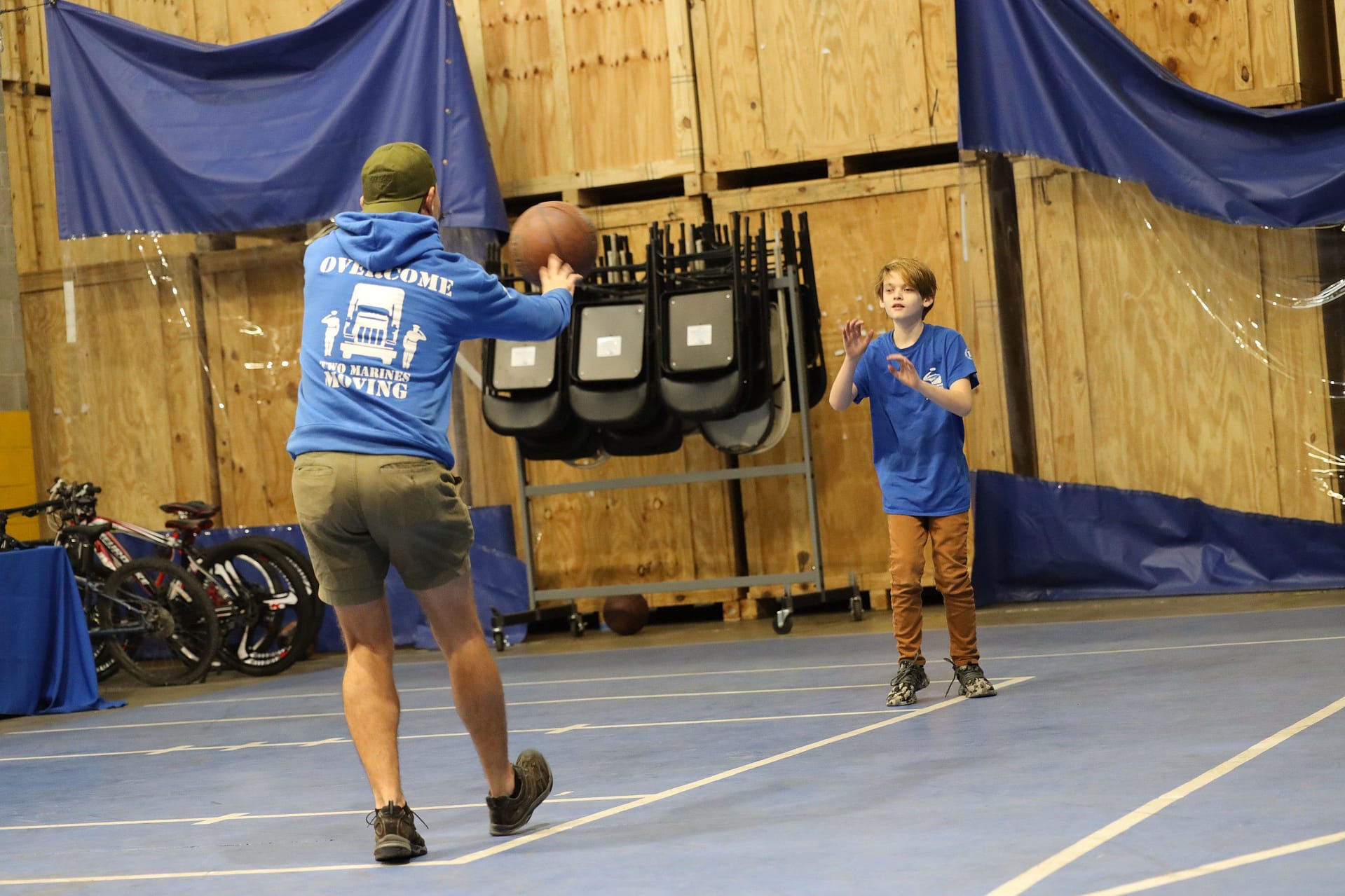 Two boys playing basketball indoors, one preparing to shoot.