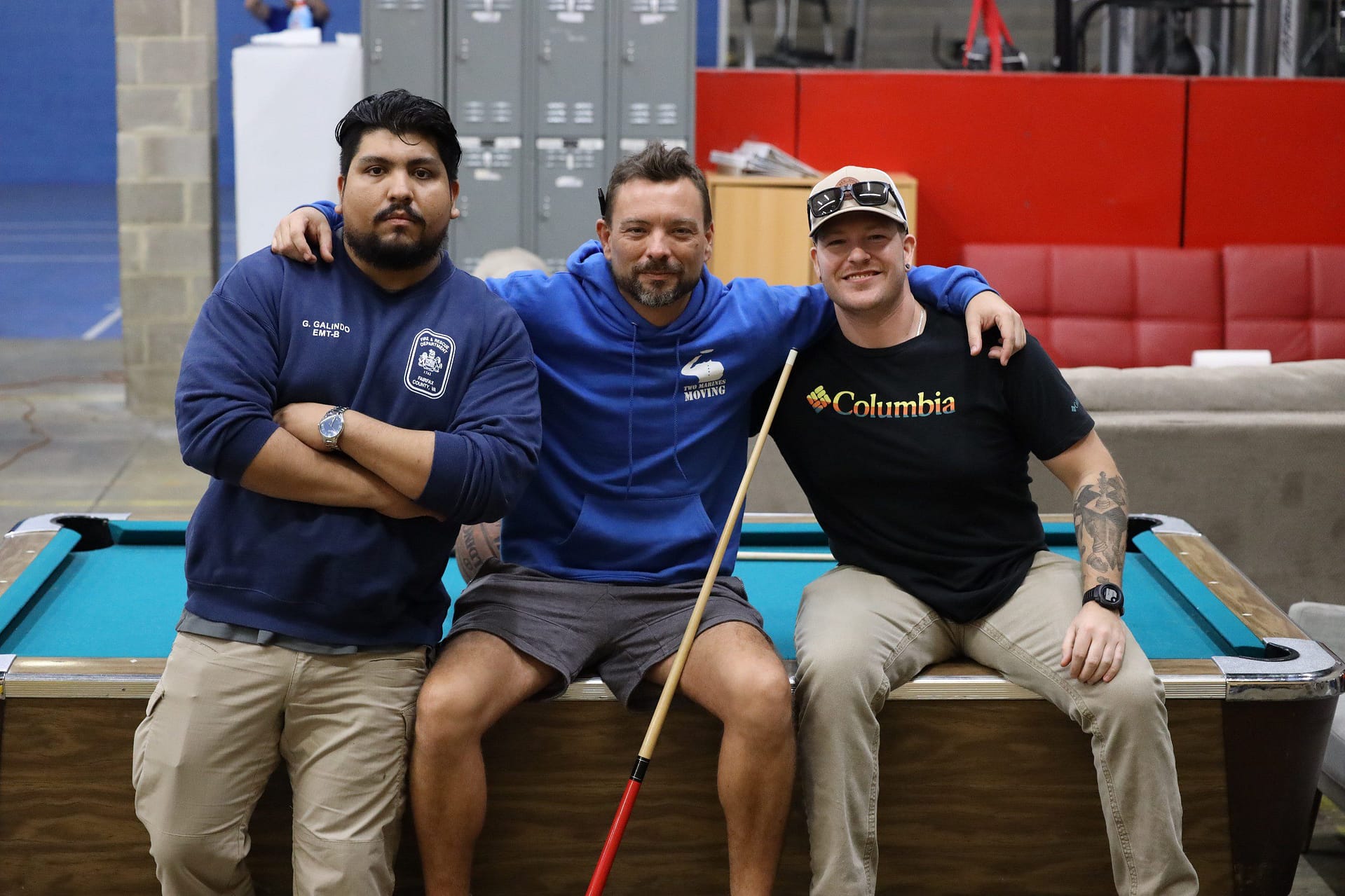 Three men posing together indoors, smiling and relaxed.