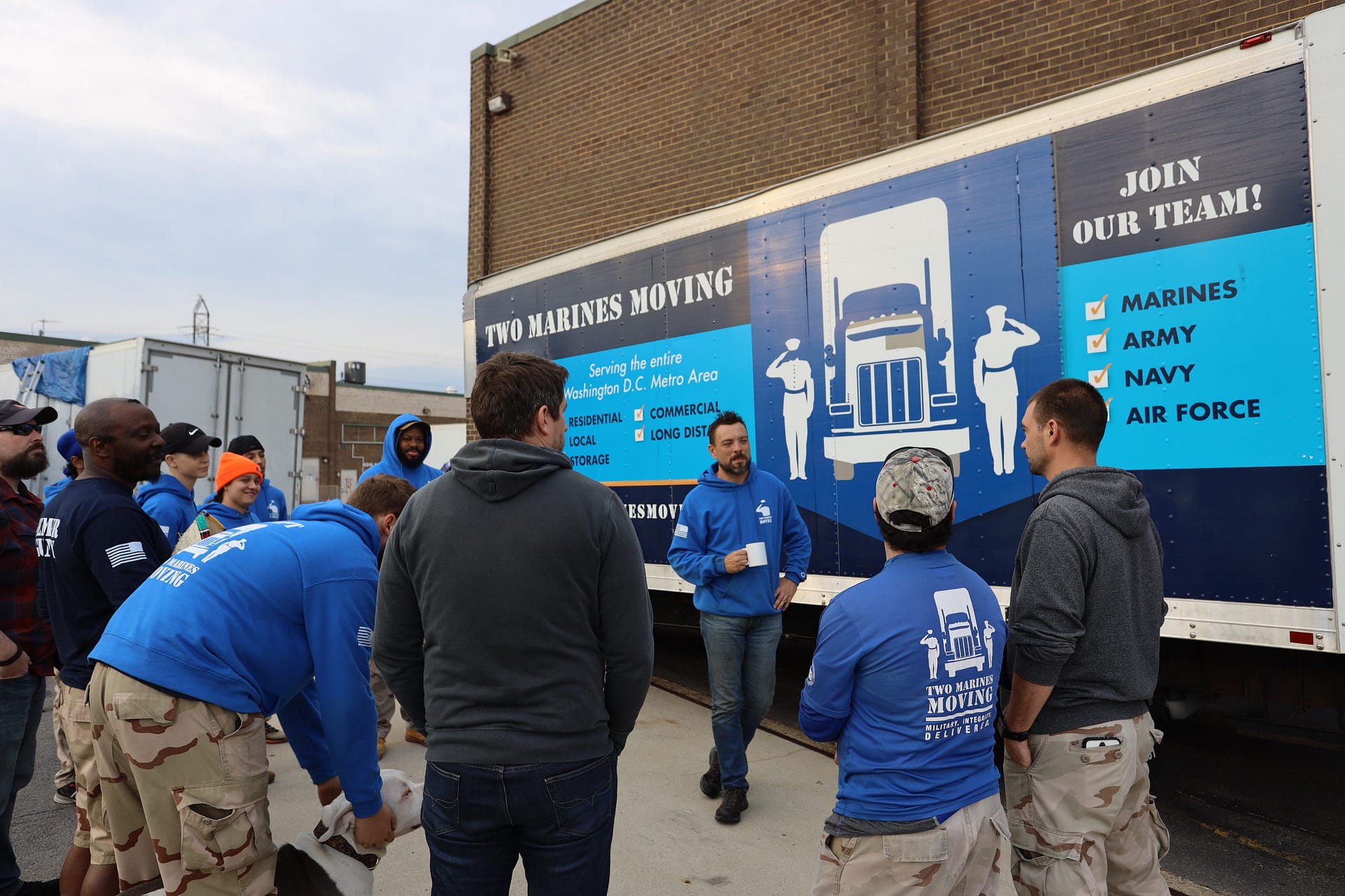 Workers gathered outside, preparing for a move with branded uniforms and truck visuals.