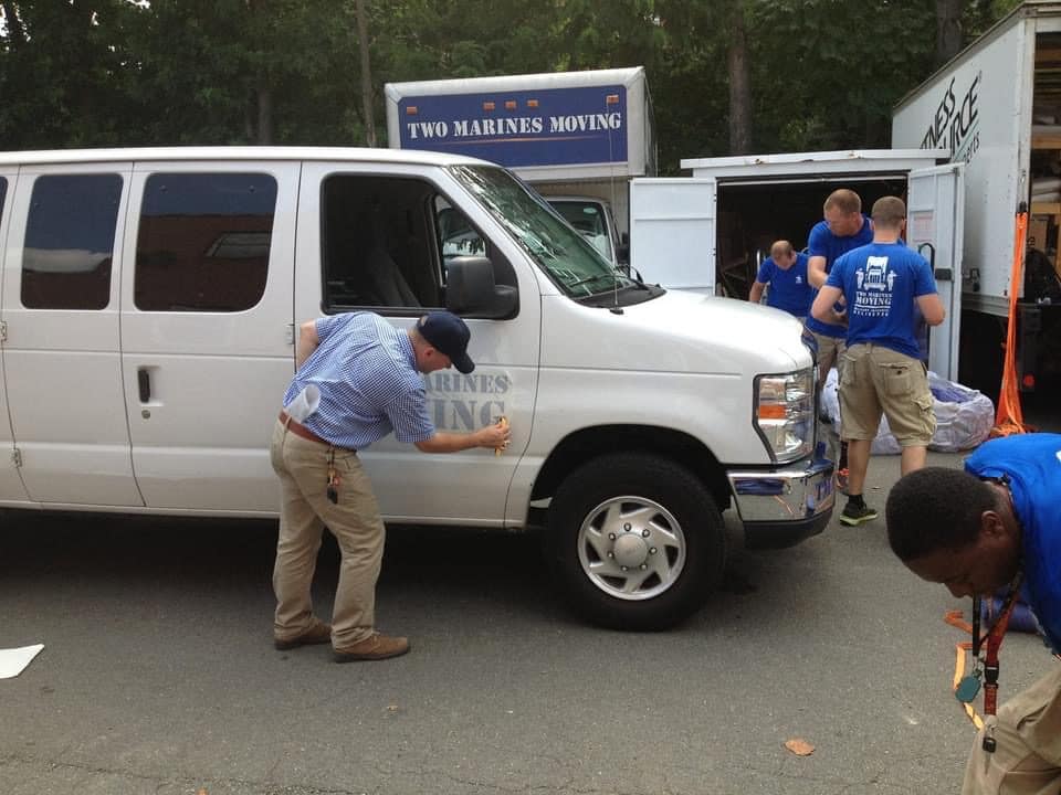 A man inspecting the side of a white van while others stand nearby.